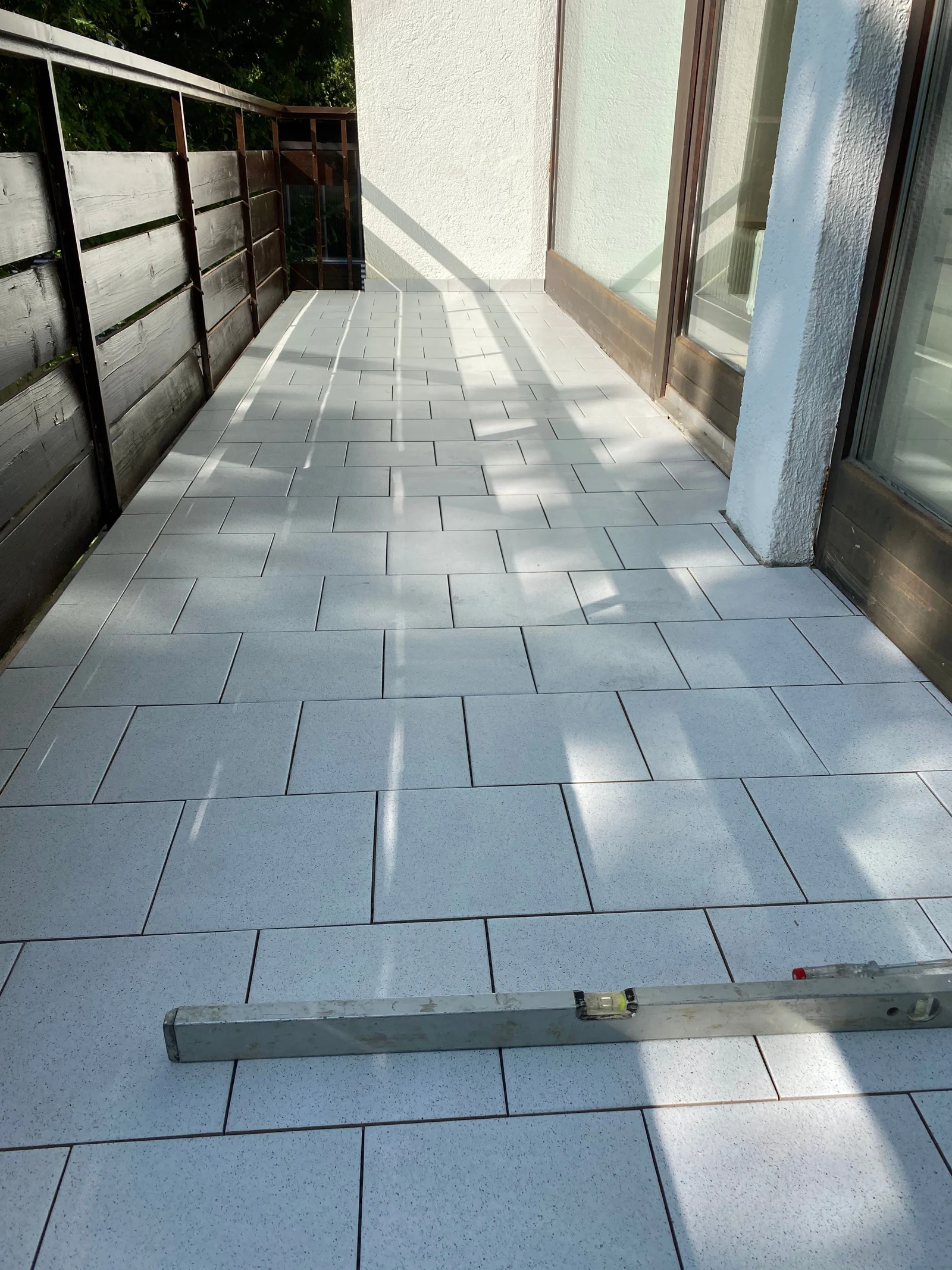 Balkon mit hellgrauen rechteckigen Bodenplatten