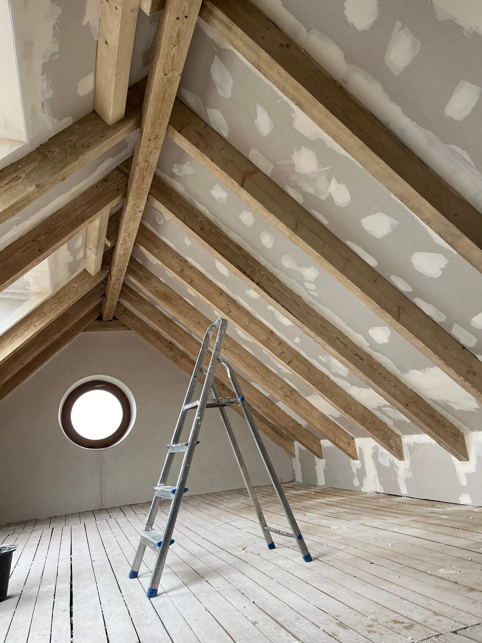 Ausgebautes Dachgeschoss mit sichtbaren Holzbalken und verspachtelten Trockenbauflächen